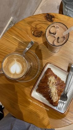 a wooden table topped with a plate of food and two cups of coffee next to each other