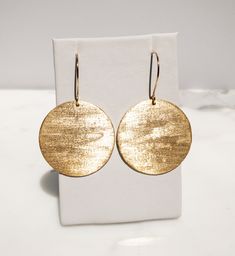 Are you looking for a unique and beautifully handcrafted accessory? Look no further than this handmade textured gold brass disc Earrings! As a single artisan handmade business based in California, I take pride in creating each pair of earrings with the utmost care and attention to detail. These earrings measure 2 inches long (including the ear wire) and 1.5 inches wide.  They are hand-textured for a unique look that makes them sparkle. They're made of solid brass.  The ear wires are also hand-made by me of 14k Gold-Fill. I believe in the quality of my work, which is why I offer a Happiness Guarantee. If for any reason you're not completely satisfied with your purchase, you can return it within 30 days for a full refund. These handmade textured gold brass circle disc earrings also make a wo 14k Gold Filled Round Earrings, Handmade 14k Gold Earrings For Everyday, Elegant Hammered Round Earrings, Gold Round Earrings For Everyday, Adjustable Hammered Earrings For Anniversary, Yellow Gold Circle Brass Earrings, Elegant Hammered Everyday Earrings, Yellow Gold Circle Earrings In Brass, Nickel-free Recycled Gold Earrings As Gift