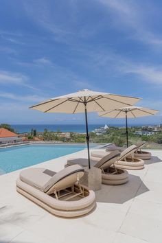 lounge chairs and umbrellas are on the patio by the pool