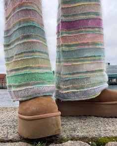 the legs and feet of a person wearing slippers with multicolored knits