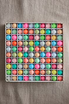 a box filled with lots of different colored candies on top of a gray surface