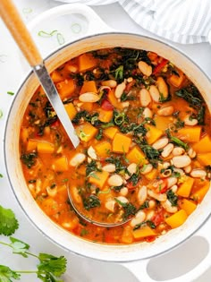 a pot filled with beans, spinach and carrots on top of a table