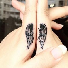 two small black angel wings tattoo on both hand and finger, with the words'tiny tattoos you want to fly into my tattoo '