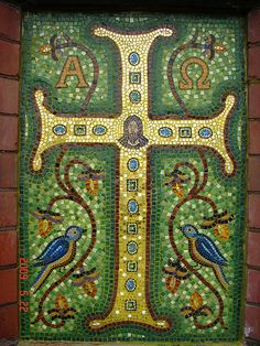 a cross with two birds on it is painted in green and yellow mosaic tiles,