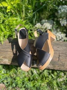 Astoria is a cross over sandal with open toe and an adjustable heel strap. The clog sandals come in black vegetable tanned leather and on mid natural soles. The vegetable tanned leather has a natural finish and should be kept away from water as it is sensitive to water stains but it will age with a beautiful rich patina. Heel height: 7 cm Platform height: 2.5 cm Fit: Narrow to medium width Leather Upper: Portuguese pull up leather Wood: Varnished lime wood Footbed: Natural wood for excellent moi Black Slingback Sandals With Wooden Heel, Black Slingback Sandals With High Wooden Heel, Black Slingback Mules With Rubber Sole, Black Mules With Wooden Heel And Ankle Strap, Black Mules With Leather Sole And Ankle Strap, Summer Slingback Clogs With Rubber Sole, Black Slingback Mules With Removable Insole, Black High Heel Sandals With Rubber Sole, Black Clogs With Heel Strap And Block Heel