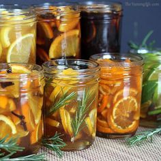 jars filled with orange slices and rosemary sprigs