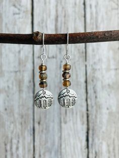 These rustic little silver dangle earrings feature beautiful mountain and pine tree stamped silver alloy charms that hang below a stack of small amber glass beads.  These unique beads have tiny hints of sky blue color, making them perfect for these outdoorsy earrings.  Everything then hangs from nickel free iron ear wires.  These earrings are light weight and perfect for everyday wear!  Earrings measure 4 cm down from earlobe and 1 cm wide. Rustic Silver Forest Earrings / Amber and Silver Dangle Earrings / Boho Earring / Mountain Earrings / Pine Tree Earrings / Nature Lover Gift I make each pair of earrings as they are ordered, so stone colors may vary from the picture.  This makes each pair uniquely yours! Click on the link below if you'd like to see all of the earrings in my shop! https: Boho Earrings Diy, Silver Forest Earrings, Forest Earrings, Mountain Earrings, Boho Earring, Rustic Earrings, Earrings Nature, Dangle Earrings Boho, Diy Jewlery