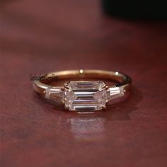 an engagement ring with three baguettes on it sitting on top of a table