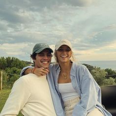 a man and woman sitting on the back of a pick up truck smiling at the camera