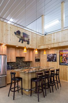 a kitchen with wooden cabinets and stools next to an island in front of a refrigerator