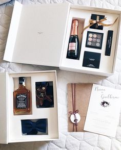 an open gift box containing two bottles of wine, a bottle of liquor and a bow tie