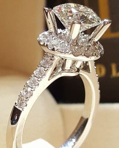 a close up view of a diamond ring on a white surface with a book in the background