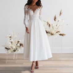 a woman wearing a white dress standing in front of flowers