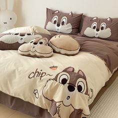 a bed with pillows and stuffed animals on the comforter, along with two pillow cases