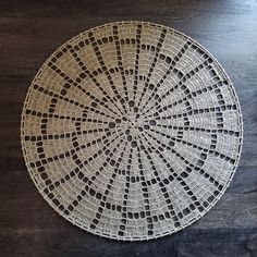 a white doily sitting on top of a wooden table next to a black wall