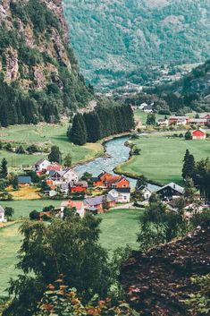 a small village in the middle of a valley with green grass and mountains behind it