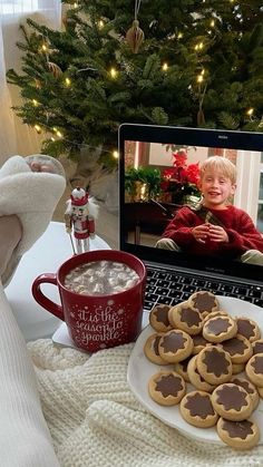 a laptop computer sitting on top of a table next to cookies and cup of coffee