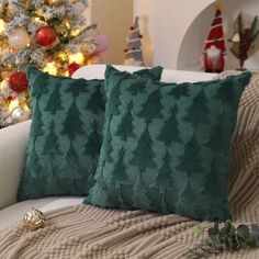 two green pillows sitting on top of a couch next to a christmas tree in the background