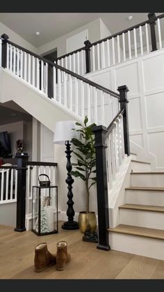 there is a lamp on the floor next to some stairs and a plant in a vase