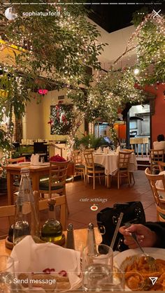 a person sitting at a table with food in front of them and lights hanging from the ceiling