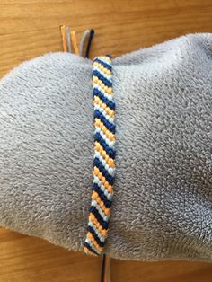 a close up of a bracelet on a person's arm with an orange and blue bead