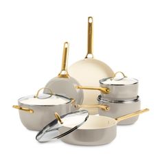 a set of pots and pans with gold handles on a white background, all in different sizes