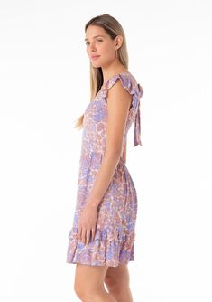 A bohemian spring cap sleeve mini dress in a retro-inspired purple floral print. Retro-inspired floral print Slim fit top Relaxed, flowy skirt Short ruffle cap sleeve Mini length Ruffle-trimmed tiered skirt Square neckline Open back with tie closure Half-smocked elastic bodice at the back Spring mini dress This style runs small; if in between sizes, we recommend sizing up We're turning up the charm this spring with this ultra-feminine mini dress. Featuring a stunning retro-inspired floral print Flowy Skirt Short, Spring Mini Dress, Spring Mini Dresses, Tiered Mini Skirt, Bohemian Dresses, Purple Floral Print, Ultra Feminine, Skirt Short, Spring Boho