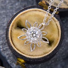 This sweet floral pendant is centered with one (1) round brilliant cut diamond, weighing 0.50 carats, set in four prongs. The diamond is surrounded by a halo of sixteen (16) round brilliant cut diamonds in shared prong settings. The pendant measures 15.0mm wide by 4.0mm thick and is signed JD & CO. The pendant hangs from a 1.3mm wide diamond cut adjustable cable chain that is 18 inches long and can be worn at 16 or 17 inches.  The chain is finished with a lobster clasp. Exquisite Diamond Flower-shaped Jewelry, Diamond White Halo Diamond Jewelry, Diamond Necklace With Halo Setting, Halo Diamond Jewelry With Round Cut, Round Cut Diamond Jewelry With Halo Detail, White Gold Moissanite Halo Design Jewelry, White Gold Moissanite Halo Jewelry, Dazzling Halo Lab Grown Diamond Jewelry, Exquisite Diamond Flower Pendant Jewelry