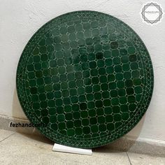 a green plate sitting on top of a tile floor next to a wall with a white base