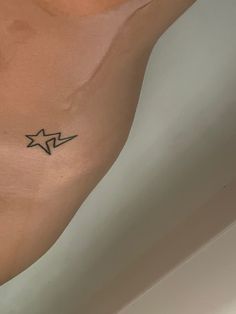 a person with a star tattoo on their left arm and chest, in the corner of a room