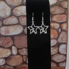 Pair of star earrings with a fairy sitting on the star. The silver color star is about 1 inch. The hooks are both nickle and lead free. Fun jewelry for any woman to wear or give as a gift Silver Star Charm Earrings, Star-shaped Crystal Earrings For Gifts, Silver Star Crystal Earrings, Silver Star Crystal Earrings For Pierced Ears, Silver Star-shaped Crystal Earrings For Pierced Ears, Silver Star-shaped Sterling Silver Earrings, Adjustable Nickel-free Silver Crystal Earrings, Sterling Silver Star Charm Drop Earrings, Sterling Silver Star Earrings In Silver