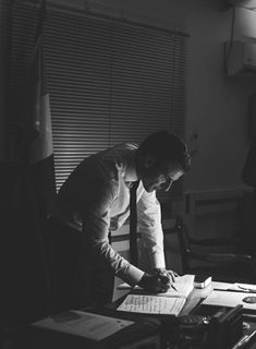 a man sitting at a desk writing on a piece of paper