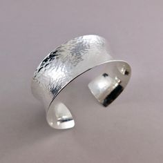 Add a touch of luxury to your jewelry collection with the Wide Concave Silver Cuff Bracelet. Expertly handcrafted from sterling silver in a wide concave shape, this bracelet has been carefully textured by hand and is incredibly comfortable to wear. Enjoy the fine details of this timeless piece and make a bold statement. Cuff is adjustable by squeezing the gap together or pulling it apart.     Product Details: * This cuff bracelet is made to order.  Will ship within 5 business days of order. * St Modern Hammered Cuff Bangle, Silver Open Cuff Bracelet With Polished Finish, Elegant Hammered Sterling Silver Bangle Bracelet, Sterling Silver Jubilee Cuff Bracelet, Elegant Hammered Sterling Silver Bangle, Modern Hammered Cuff Jewelry, Elegant Hammered Cuff Bangle, Classic Silver Open Cuff Bracelet, Elegant Sterling Silver Hammered Bangle