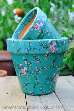 three blue flower pots sitting on top of a wooden table next to potted plants