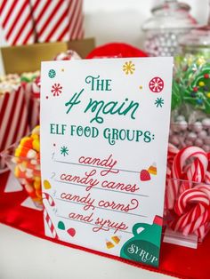 a sign that says the 4 main elf food groups next to candy canes and candies