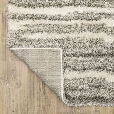 an area rug with grey and white stripes on the floor next to a wooden floor