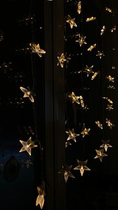 some lights that are hanging from the side of a building with stars on them in the dark