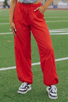 Introducing our Game On Red Parachute Pants, a must-have for game days! These lightweight pants feature a low waist and elastic waistband with an adjustable drawstring for the perfect fit. Complete with side pockets and stopper detail. Made of 50% Nylon, 45% Polyester, and 5% Spandex. It is also available in Black & White! Style it with a game day tee and your favorite sneakers to complete the look. Sporty Nylon Joggers With Drawstring, Sporty Nylon Pants With Drawstring, Sporty Stretch Parachute Pants With Drawstring, Red Sporty Activewear For Outdoor, Sporty Red Activewear For Outdoor Activities, Red Athleisure Activewear For Outdoor, Sports Parachute Pants With Drawstring, Sporty Solid Color Nylon Pants, Sporty Nylon Pants In Solid Color