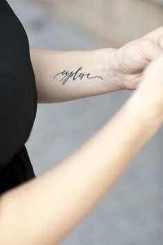 a woman with a tattoo on her arm that says, explore forearm tatoo