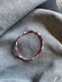 a pink beaded bracelet on top of a gray shirt