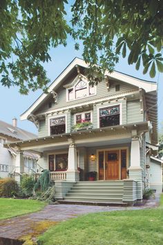 a green two story house with white trim on the front porch and windows, along with steps leading up to the second floor