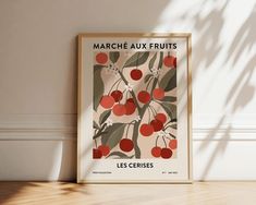 a framed poster on the wall in front of a wooden floor with a plant and fruit