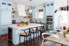 a kitchen with blue cabinets and white counter tops, wooden flooring and an island in the middle