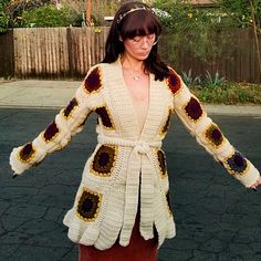 a woman in a crocheted jacket is holding her hands out to the side