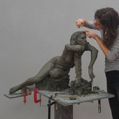 a woman is working on a statue in an art studio