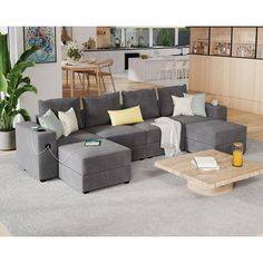 a living room with grey couches and yellow pillows on the floor in front of a wooden table