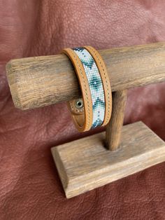 a wooden stand holding two bracelets on it's sides and a brown leather background