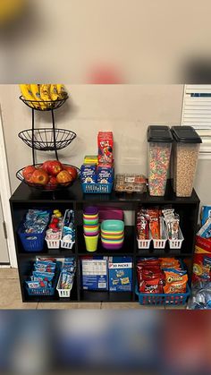 a shelf filled with lots of food next to a wall covered in plastic bins