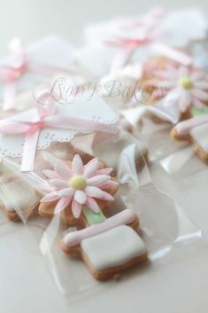 cookies decorated with pink and white icing are sitting in plastic bags on a table