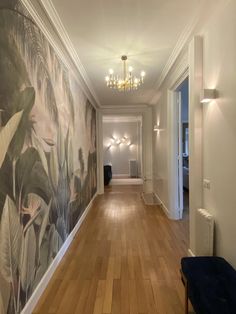 an empty hallway with wood flooring and wallpaper on the walls is lit by a chandelier